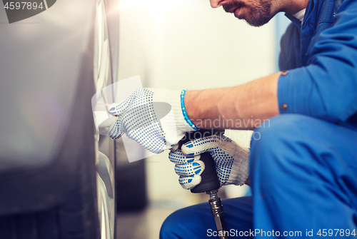 Image of mechanic with screwdriver changing car tire