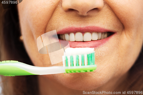 Image of senior woman with toothbrush brushing her teeth