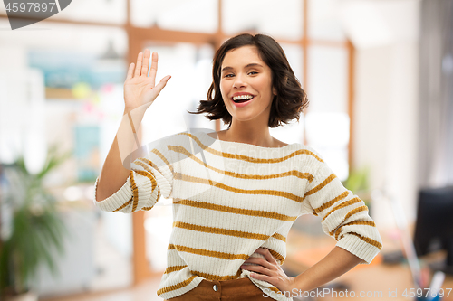 Image of smiling woman in striped pullover waving hand