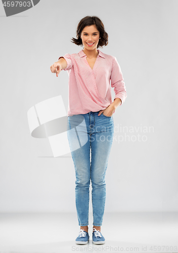 Image of young woman in shirt and jeans pointing to you