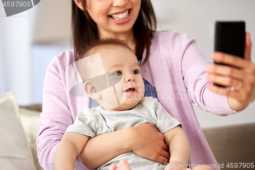 Image of asian mother with baby son taking selfie at home