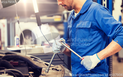 Image of mechanic man with wrench repairing car at workshop