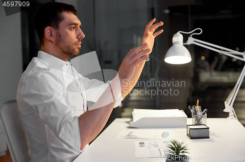 Image of businessman using gestures at night office