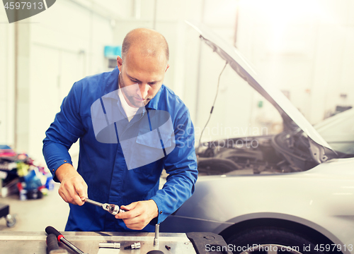 Image of mechanic man with wrench repairing car at workshop