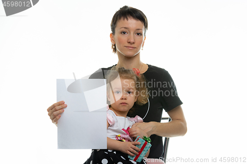 Image of Mom and baby sit on a chair and hold a white sheet in their hands