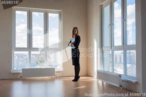 Image of Realtor expects buyers in a large room with huge windows