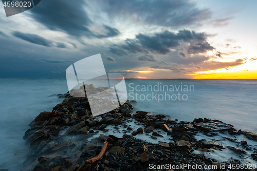 Image of Sea sunset after sunset, in the foreground a breakwater of stones