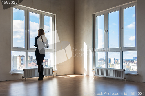 Image of A girl looks into large stained glass windows in an empty apartment