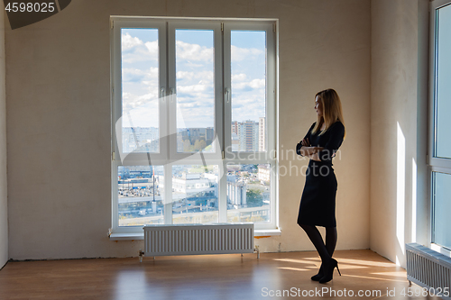 Image of Slender girl stands at a large stained glass window in an empty room