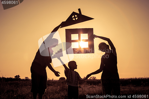 Image of Happy family standing on the field at the sunset time. They buil