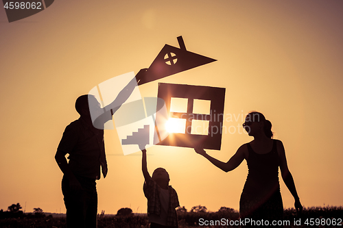 Image of Happy family standing on the field at the sunset time. They buil