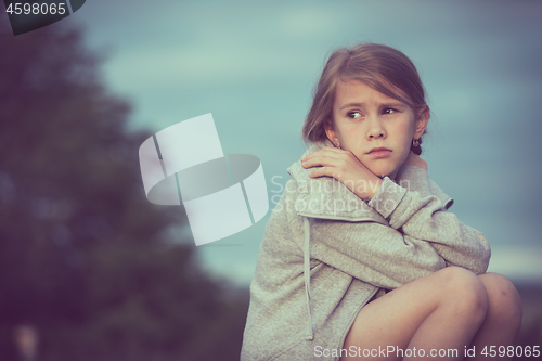 Image of Portrait of young sad girl sitting outdoors  on the railway