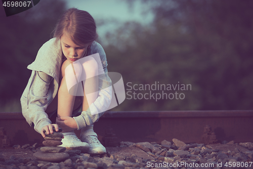 Image of Portrait of young sad girl sitting outdoors  on the railway