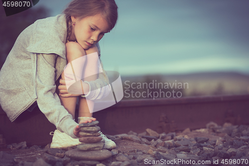 Image of Portrait of young sad girl sitting outdoors  on the railway