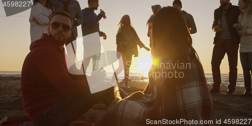 Image of Friends having fun at beach on autumn day