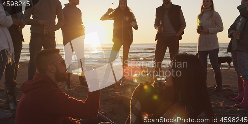 Image of Friends having fun at beach on autumn day