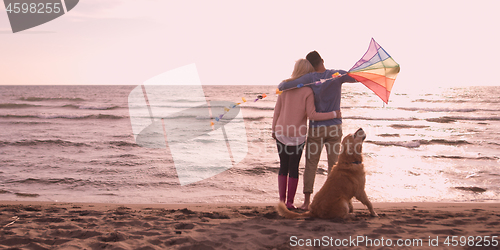 Image of couple with dog having fun on beach on autmun day