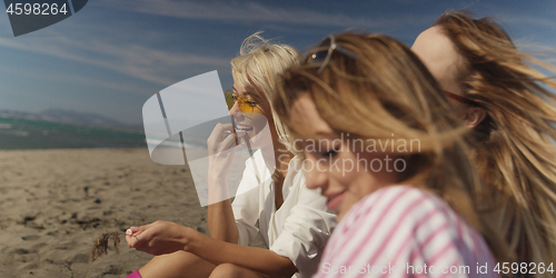 Image of Group of girlfriends having fun on beach during autumn day