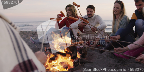 Image of Group Of Young Friends Sitting By The Fire at beach