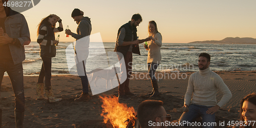 Image of Friends having fun at beach on autumn day