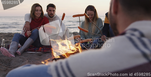 Image of Group Of Young Friends Sitting By The Fire at beach