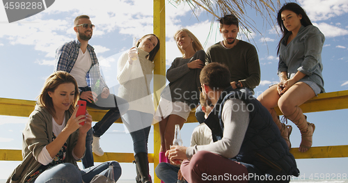 Image of Group of friends having fun on autumn day at beach