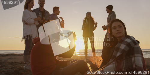 Image of Friends having fun at beach on autumn day