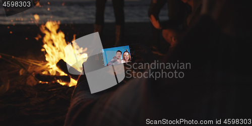 Image of Couple taking photos beside campfire on beach