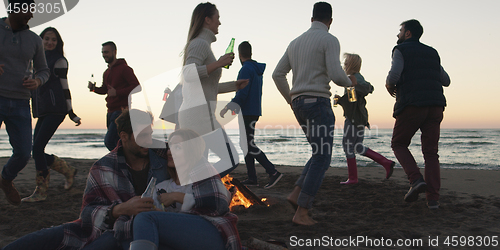 Image of Friends having fun at beach on autumn day