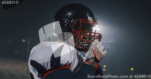 Image of American Football Player Putting On Helmet on large stadium with