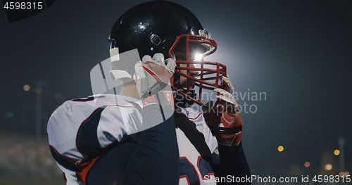 Image of American Football Player Putting On Helmet on large stadium with