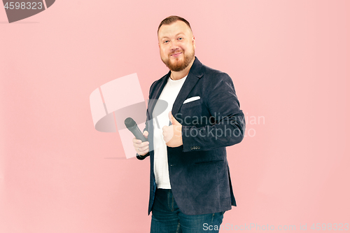 Image of Young man with microphone on pink background, leading with microphone