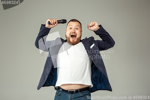 Image of Young man with microphone on gray background, leading with microphone