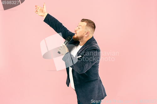 Image of Young man with microphone on pink background, leading with microphone