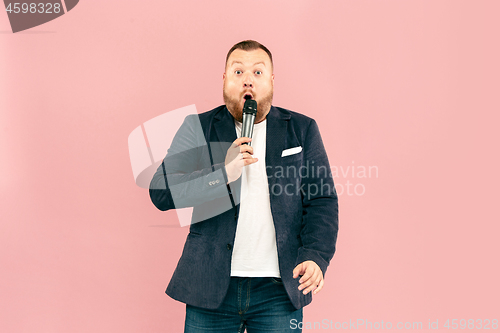 Image of Young man with microphone on pink background, leading with microphone