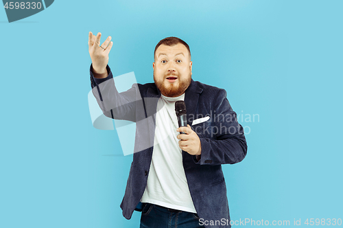 Image of Young man with microphone on blue background, leading concept