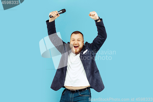 Image of Young man with microphone on blue background, leading concept