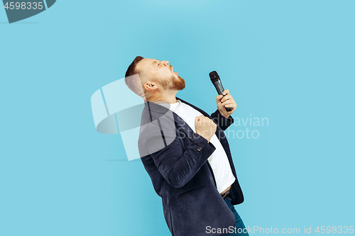 Image of Young man with microphone on blue background, leading concept