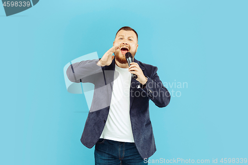 Image of Young man with microphone on blue background, leading concept