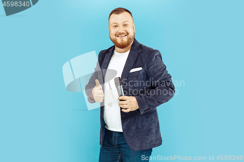 Image of Young man with microphone on blue background, leading concept