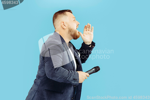 Image of Young man with microphone on blue background, leading concept