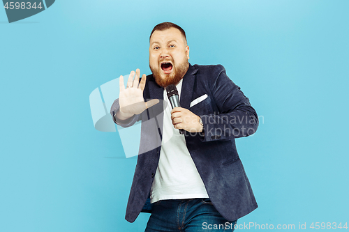 Image of Young man with microphone on blue background, leading concept