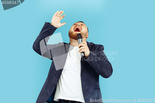 Image of Young man with microphone on blue background, leading concept