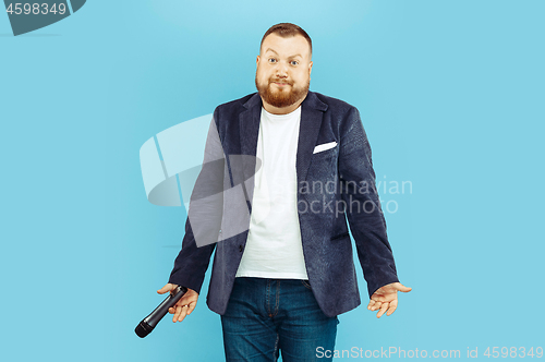 Image of Young man with microphone on blue background, leading concept