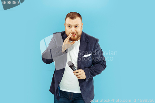 Image of Young man with microphone on blue background, leading concept