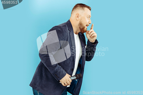 Image of Young man with microphone on blue background, leading concept