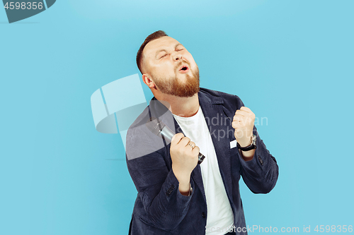 Image of Young man with microphone on blue background, leading concept