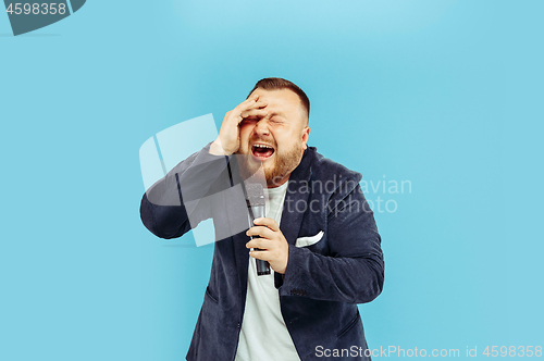 Image of Young man with microphone on blue background, leading concept