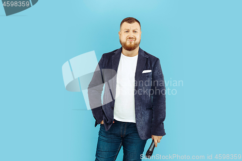 Image of Young man with microphone on blue background, leading concept