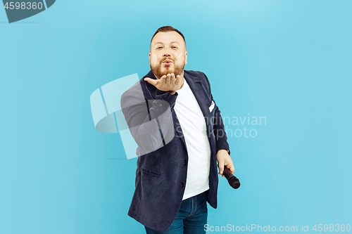 Image of Young man with microphone on blue background, leading concept